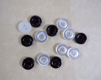May include: A collection of black and white buttons with two holes each. The buttons are oval shaped and have a smooth, shiny finish.