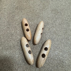 May include: Four wooden toggle buttons with two holes each. The buttons are light brown and have a natural wood grain.