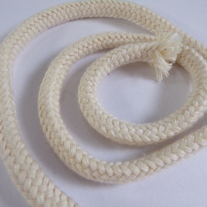 May include: A close-up of a white cotton rope, braided in a simple pattern. The rope is coiled in a circle, with the ends of the rope visible.