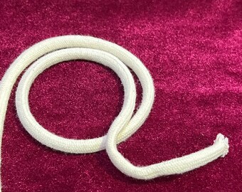 May include: A close-up of a white cotton cord on a burgundy velvet background. The cord is coiled in a circle.