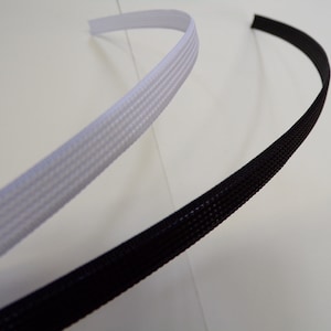 May include: Two pieces of black and white braided cord, one black and one white, are shown on a white background. The cords are flexible and have a woven texture.