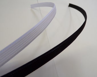 May include: Two pieces of black and white braided cord, one black and one white, are shown on a white background. The cords are flexible and have a woven texture.