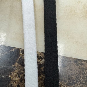 May include: Two strips of fabric, one white and one black, are shown side-by-side. Both strips are fuzzy and have a textured surface.