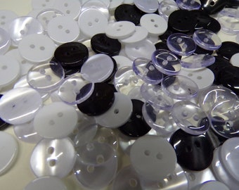 May include: A collection of assorted buttons in white, black, and clear plastic. The buttons are round and have two holes.