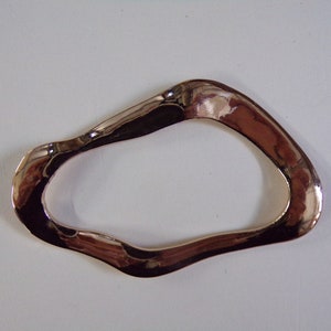May include: A smooth, metallic, rose gold coloured, open ring with an irregular, wavy shape.