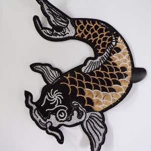 May include: Black and gold embroidered iron-on patch of a koi fish with white details.