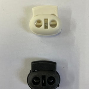 May include: Two toggle clasps, one white and one black. Both clasps have two holes and a small metal piece in the center.