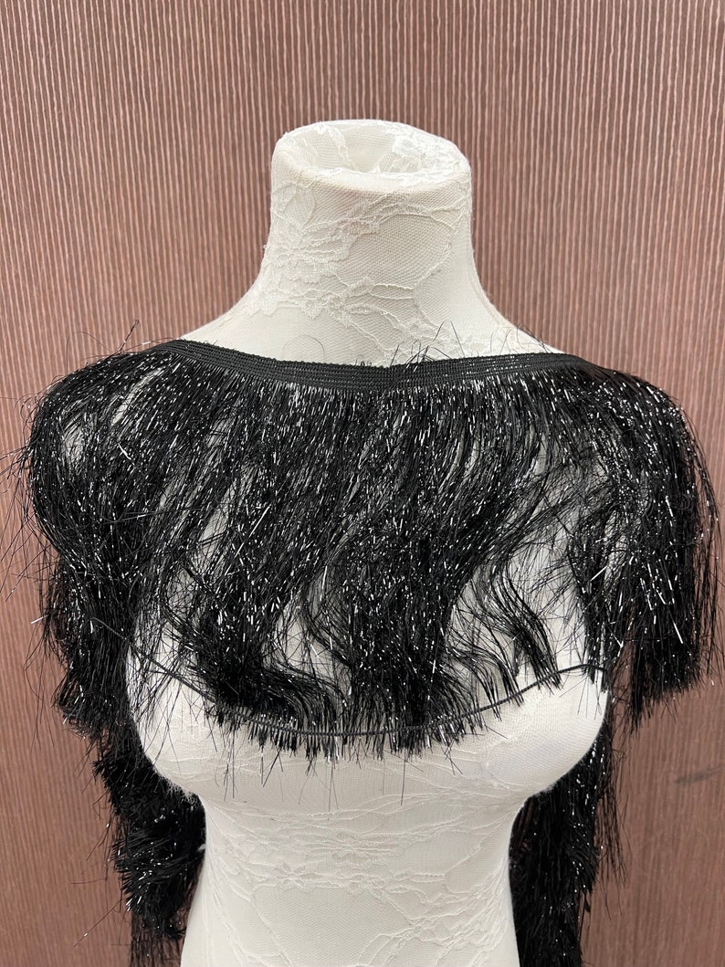 May include: Black fringe trim with a sparkly finish. The fringe is about 2 inches long.