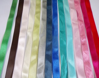 May include: Assortment of 14 satin ribbon spools in various colours, including green, brown, white, cream, yellow, grey, blue, turquoise, teal, light blue, pink, light pink, magenta, and red.