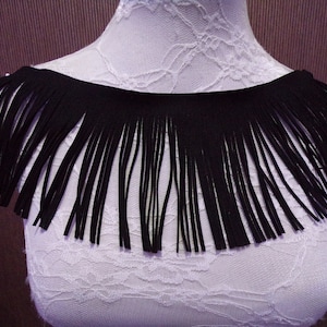 May include: Black fringe trim with a smooth, even texture. The fringe is approximately 5 cm long.