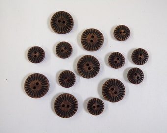 May include: A collection of 12 brown wooden buttons with a decorative floral design. Each button has two holes and a raised center.