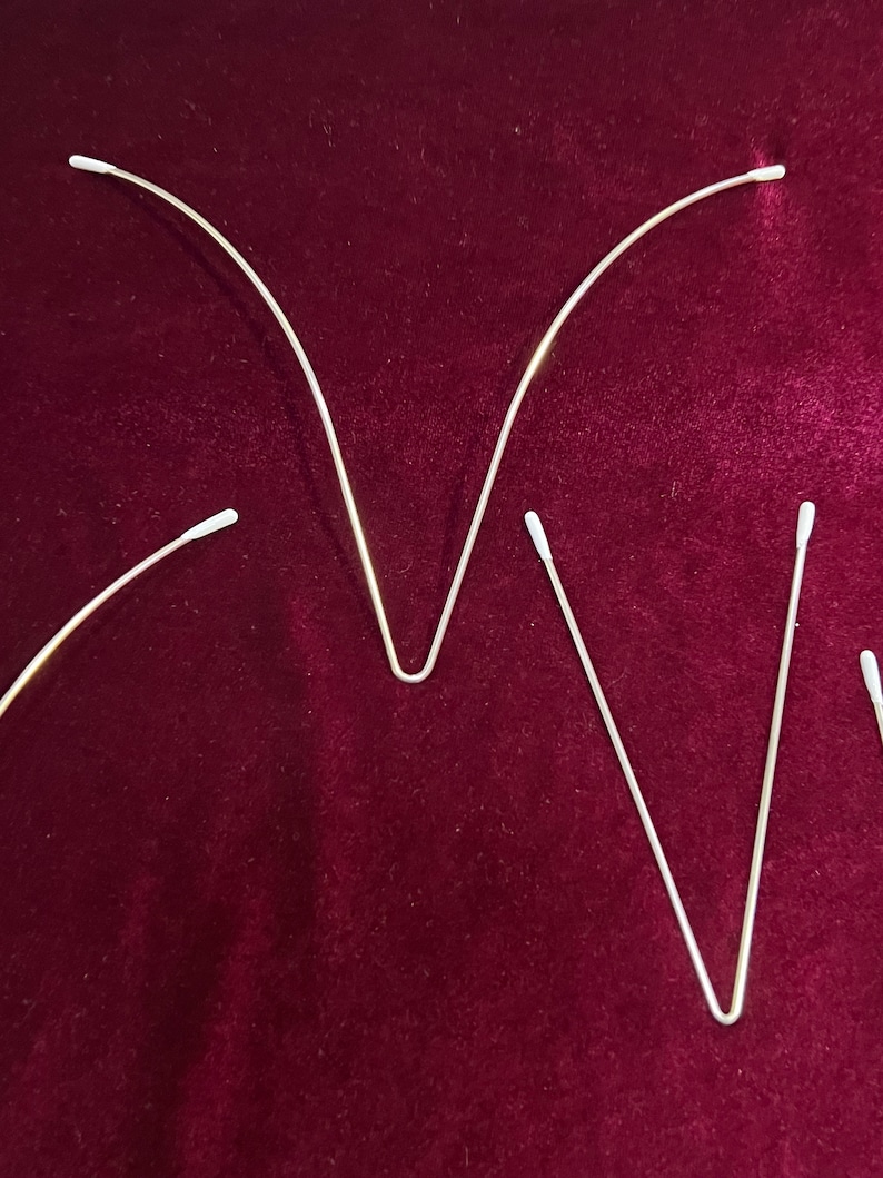 May include: Three bent metal rods with white cotton tips on each end. The rods are arranged in a V shape, with the tips pointing upwards.