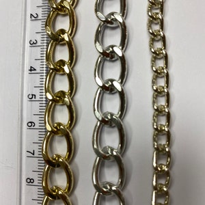 May include: Three chains of different styles and colors. The chain on the left is gold and has large oval links. The chain in the middle is silver and has smaller oval links. The chain on the right is gold and has small square links.