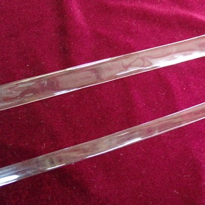 May include: Two clear plastic strips on a red velvet background.