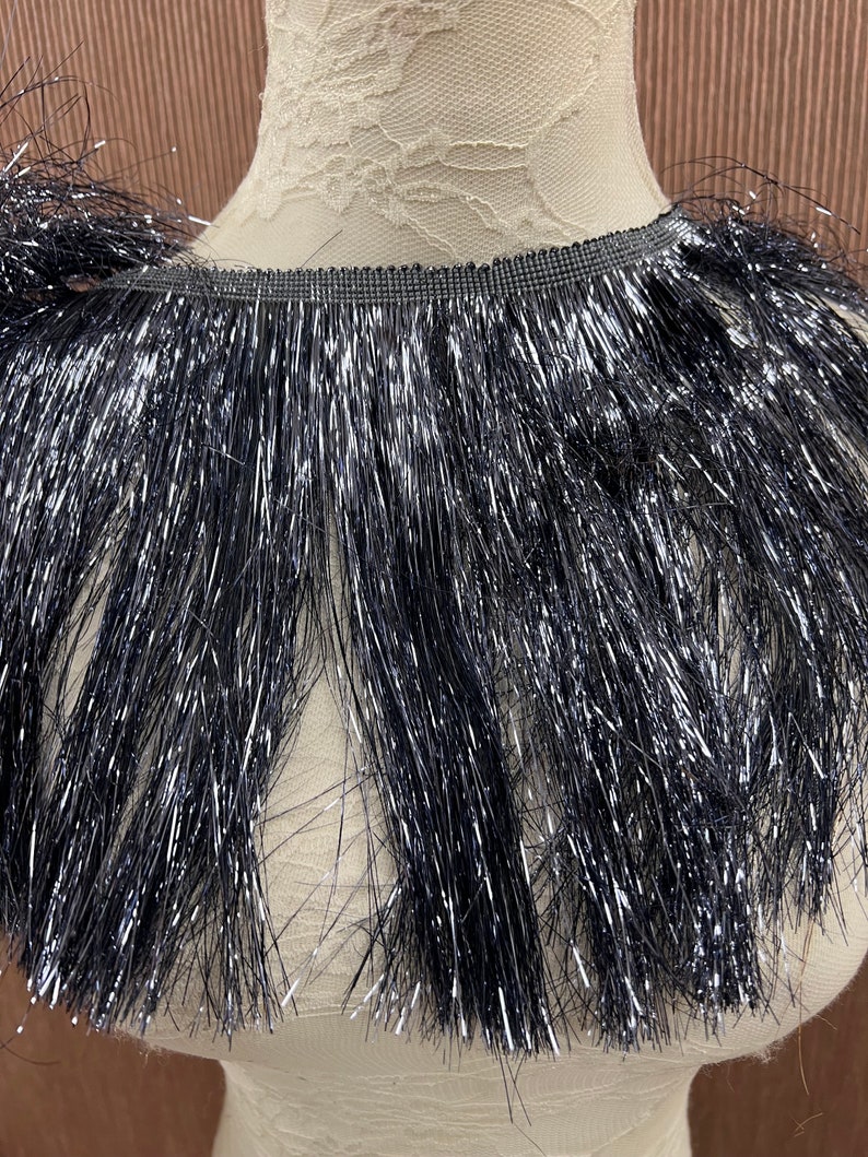 May include: Black fringe trim with silver glitter. The fringe is about 2 inches long.