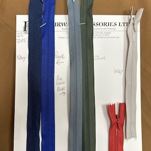 May include: Assortment of zipper pulls in various colors, including navy, royal blue, air force blue, gray, olive, red, and tan. The zipper pulls are labeled with their corresponding colors.