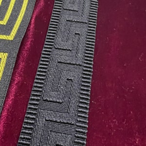 Puede incluir: Dos tiras de adorno decorativo con un patr&oacute;n geom&eacute;trico. Una tira es gris con un dise&ntilde;o amarillo, y la otra es gris con un patr&oacute;n texturizado en relieve. El adorno se utiliza probablemente para bordear o embellecer.