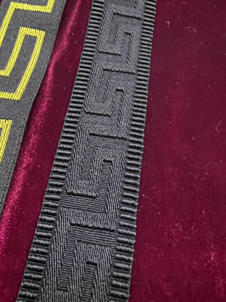 Puede incluir: Dos tiras de adorno decorativo con un patr&oacute;n geom&eacute;trico. Una tira es gris con un dise&ntilde;o amarillo, y la otra es gris con un patr&oacute;n texturizado en relieve. El adorno se utiliza probablemente para bordear o embellecer.