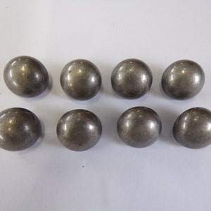 May include: Eight silver-toned round buttons with a slightly textured surface.