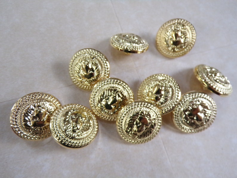 Puede incluir: Diez botones de color dorado con un dise&ntilde;o de cabeza de le&oacute;n en relieve. Los botones tienen un borde circular texturizado.