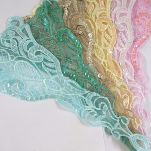 Puede incluir: Un surtido arcoíris de encaje con lentejuelas y borde festoneado. El encaje es en tonos azul claro, verde, amarillo y rosa.
