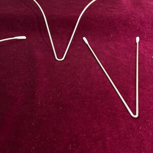 May include: Three white cotton swabs with a thin metal wire bent into a V shape.