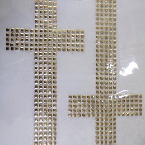 May include: Two gold cross-shaped iron-on patches. Each patch is made of small square rhinestones.