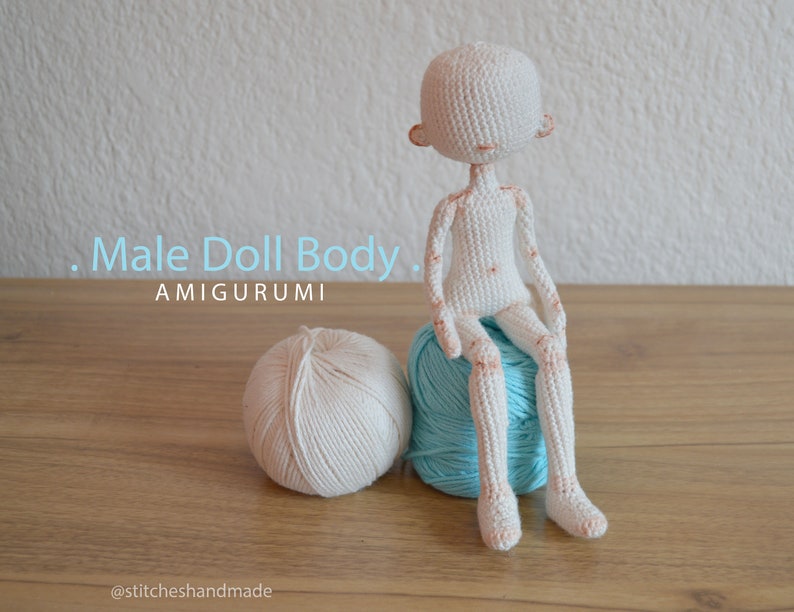 May include: White crocheted amigurumi doll body sitting on a blue yarn ball. The doll has a simple face and is sitting with its legs crossed. The text "Male Doll Body" and "AMIGURUMI" is visible in the image. The text "@stitcheshandmade" is visible at the bottom of the image.