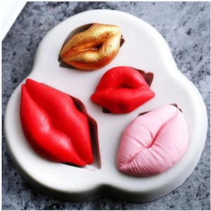 May include: Silicone mould for making lip-shaped sweets or chocolates. The mould has four cavities, each shaped like a pair of lips. The lips are in different colours: gold, red, pink, and red.