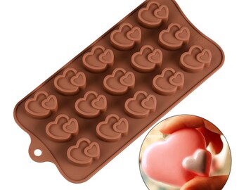 May include: Brown silicone mold with 15 heart-shaped cavities. Each cavity features two hearts, one slightly smaller than the other. The mold is designed for making chocolate or other treats.