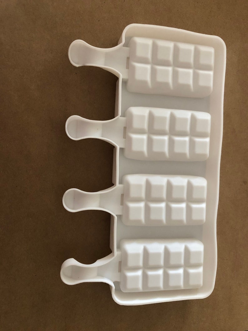 May include: White silicone popsicle mold with four individual molds, each with a rectangular shape and a textured surface. Each mold has a handle for easy removal.