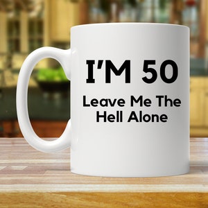 May include: White ceramic coffee mug with black text that reads "I'm 50 Leave Me The Hell Alone".