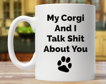 May include: White ceramic coffee mug with black text that reads "My Corgi And I Talk Shit About You" with a black paw print below the text.