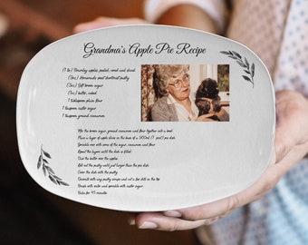 Peut inclure: Plat de service ovale blanc avec une photo en noir et blanc d'une femme tenant un chien. Le plat porte une recette manuscrite pour la tarte aux pommes de grand-mère.