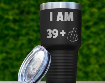 May include: Black stainless steel tumbler with a lid. The tumbler has the text "I AM 39+" and a middle finger emoji engraved on it.