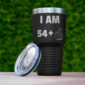May include: Black stainless steel tumbler with a lid. The tumbler has the text "I AM 54+" and a middle finger emoji engraved on it.