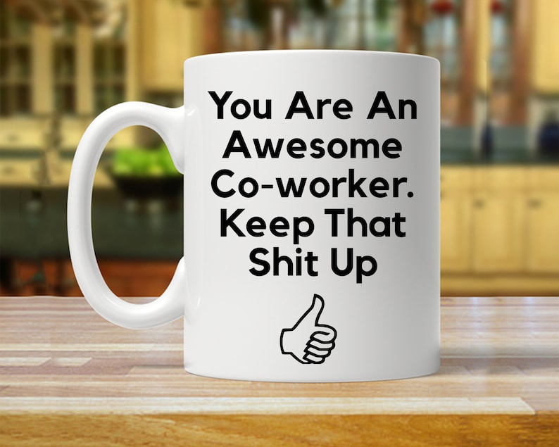 May include: White ceramic coffee mug with black text that reads "You Are An Awesome Co-worker. Keep That Shit Up" and a thumbs up icon.