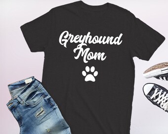 May include: Black t-shirt with white text that says "Greyhound Mom" and a white paw print.
