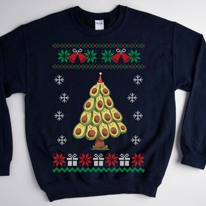 May include: A navy blue Christmas sweater with a green, red, and white pattern. The sweater features a Christmas tree made of avocados with a red Santa hat on top. The tree is surrounded by snowflakes and presents.