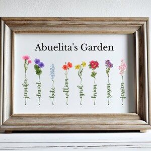 May include: A framed print with the title "Abuelita's Garden" featuring a watercolor illustration of nine different flowers with names written underneath each flower: Jennifer, David, Kate, William, April, Brian, Susan, and Jessica.