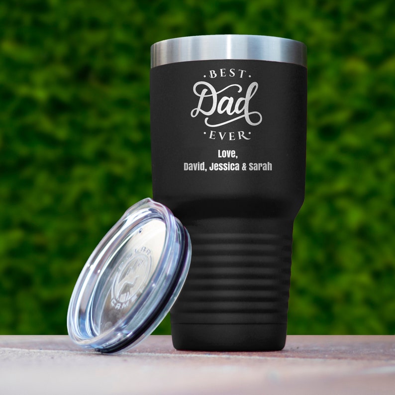 May include: Black stainless steel tumbler with a lid. The tumbler has an engraved design that says "Best Dad Ever" and "Love, David, Jessica & Sarah".