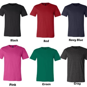 Puede incluir: Seis camisetas de diferentes colores: negro, rojo, azul marino, rosa, verde y gris. Las camisetas son todas del mismo estilo, con cuello redondo y mangas cortas.