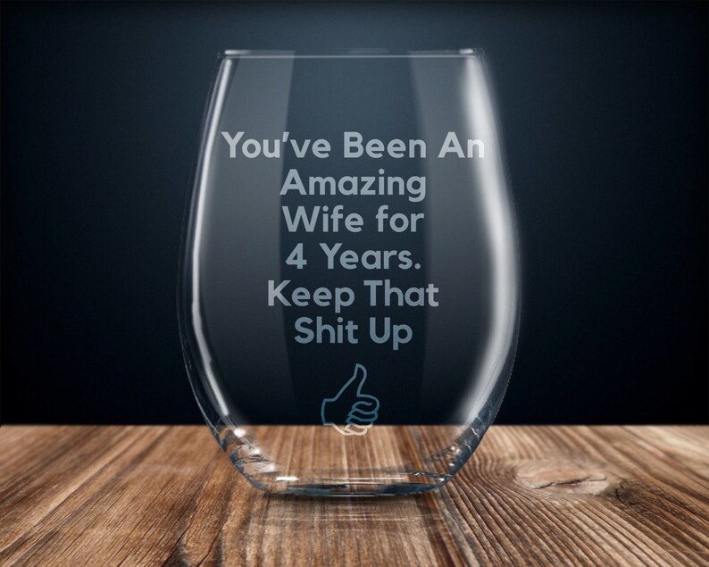 May include: A clear glass wine glass with the text "You've Been An Amazing Wife for 4 Years. Keep That Shit Up" etched on the side. A thumbs up icon is also etched on the glass.