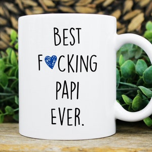 May include: White ceramic coffee mug with black text that reads "BEST FOCKING PAPI EVER." A blue heart is in place of the "O" in "FOOKING".
