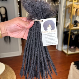 May include: A bundle of black dreadlock extensions. The dreadlocks are about 20 inches long and are made of synthetic hair. The dreadlocks are tied together with a string. The image includes the text "Legacy Locs Dreadlock Extensions Hair Collection Phone: (678)729-7051 Email: info@LegacyLocs.com Instagram: @Legacylocs TikTok@LegacyLocaLLC www.Facebook.com/LegacyLocs LegacyLocs.com"