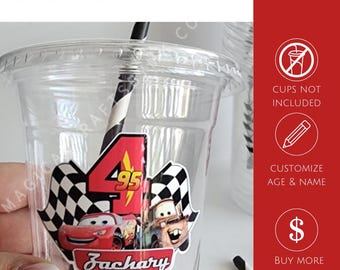 May include: A clear plastic cup featuring a sticker with the number 4, the text 95, and the name Zachary, alongside images of two race cars and checkered flags. The text STICKERS ONLY, CUPS NOT INCLUDED, CUSTOMIZE AGE & NAME, and BUY MORE SAVE MORE appear.