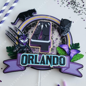 May include: A Black Panther-themed cake topper featuring the name "Orlando" in teal and black. The number "4" is central, accompanied by a Black Panther figure, a panther silhouette, and purple details. Ideal for a birthday party.