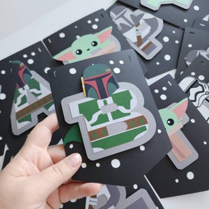 May include: A black and white banner with a Star Wars theme. The banner features characters like Yoda, Boba Fett, and Darth Vader. The banner is decorated with white polka dots.
