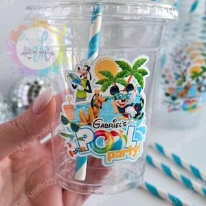 May include: A clear plastic cup with a lid and a blue and white striped straw. The cup features a colorful decal of cartoon characters at a pool party with the text Gabriel's Pool Party, including a sun, palm trees, and a beach ball.