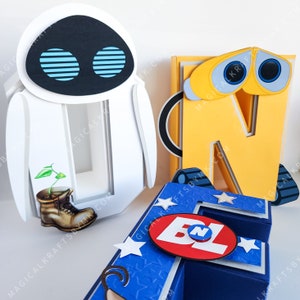 May include: Papercraft figures of the characters Eve and Wall-E from the animated film. The Wall-E figure is yellow with blue eyes and treads. The Eve figure is white with blue eyes. A blue and white papercraft letter "N" is also present.